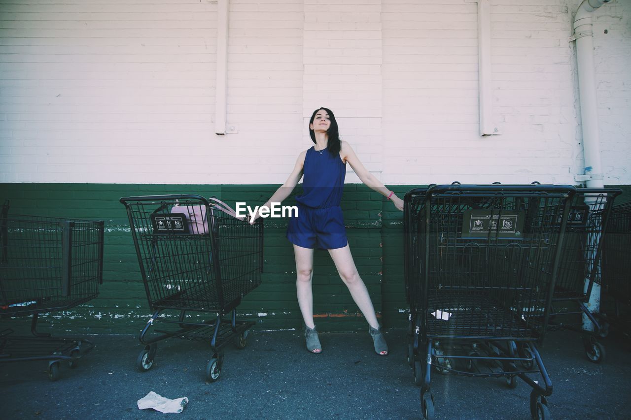 Woman standing amidst shopping carts against wall