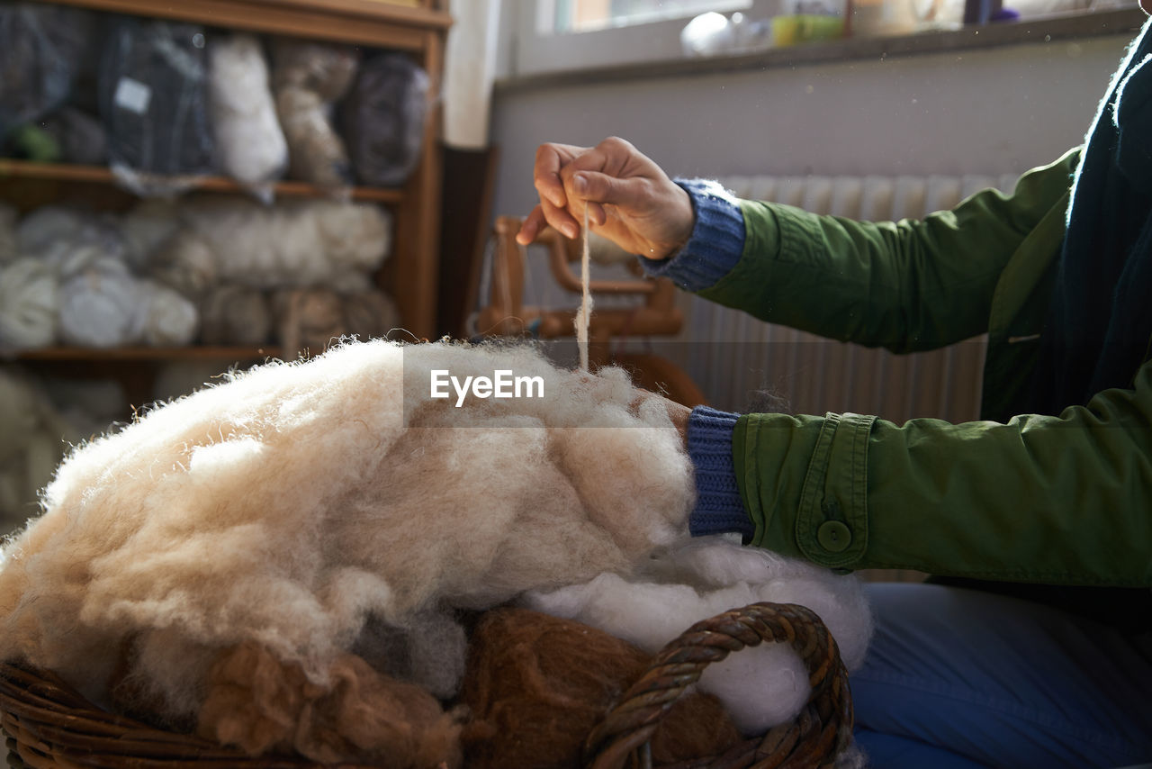 Midsection of person holding wool in basket at home