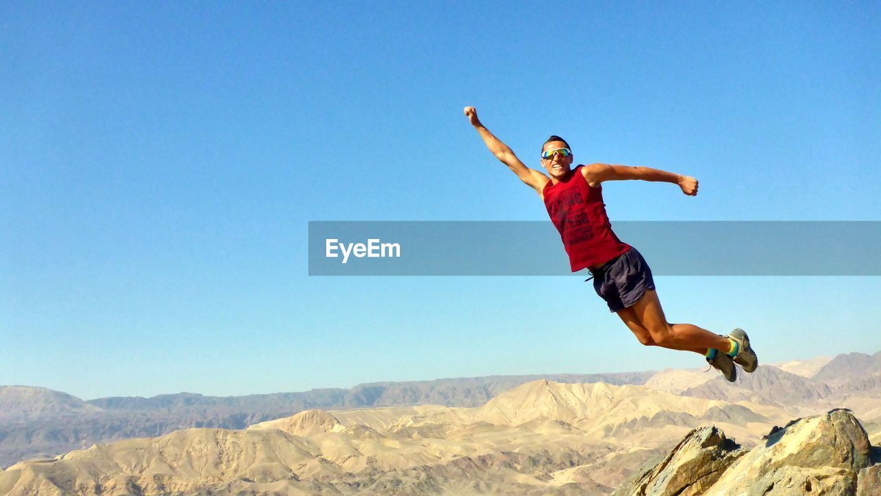 Full length of man jumping over landscape against sky