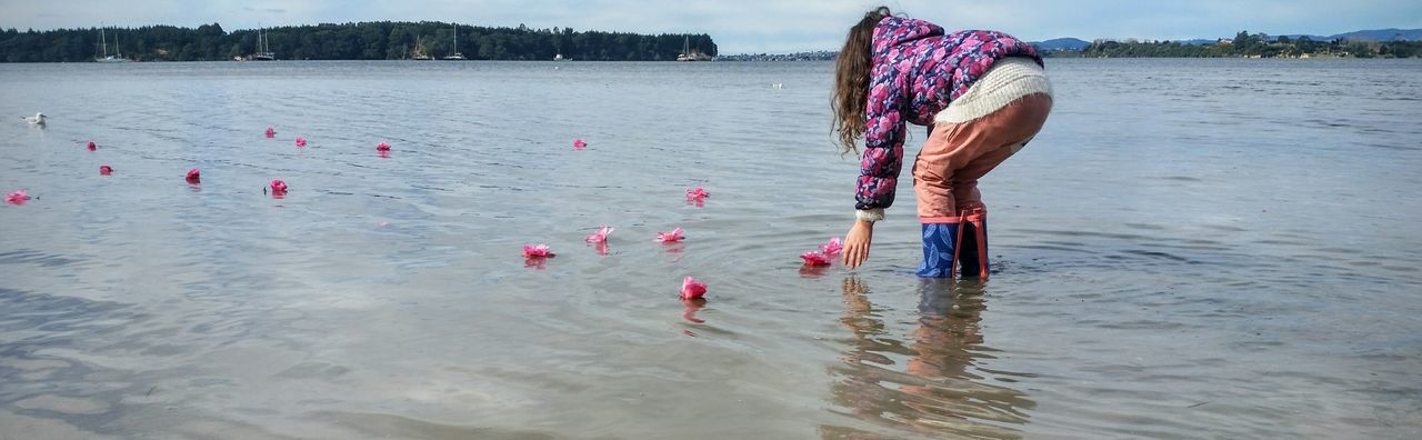 A young girl sending flowers out to sea