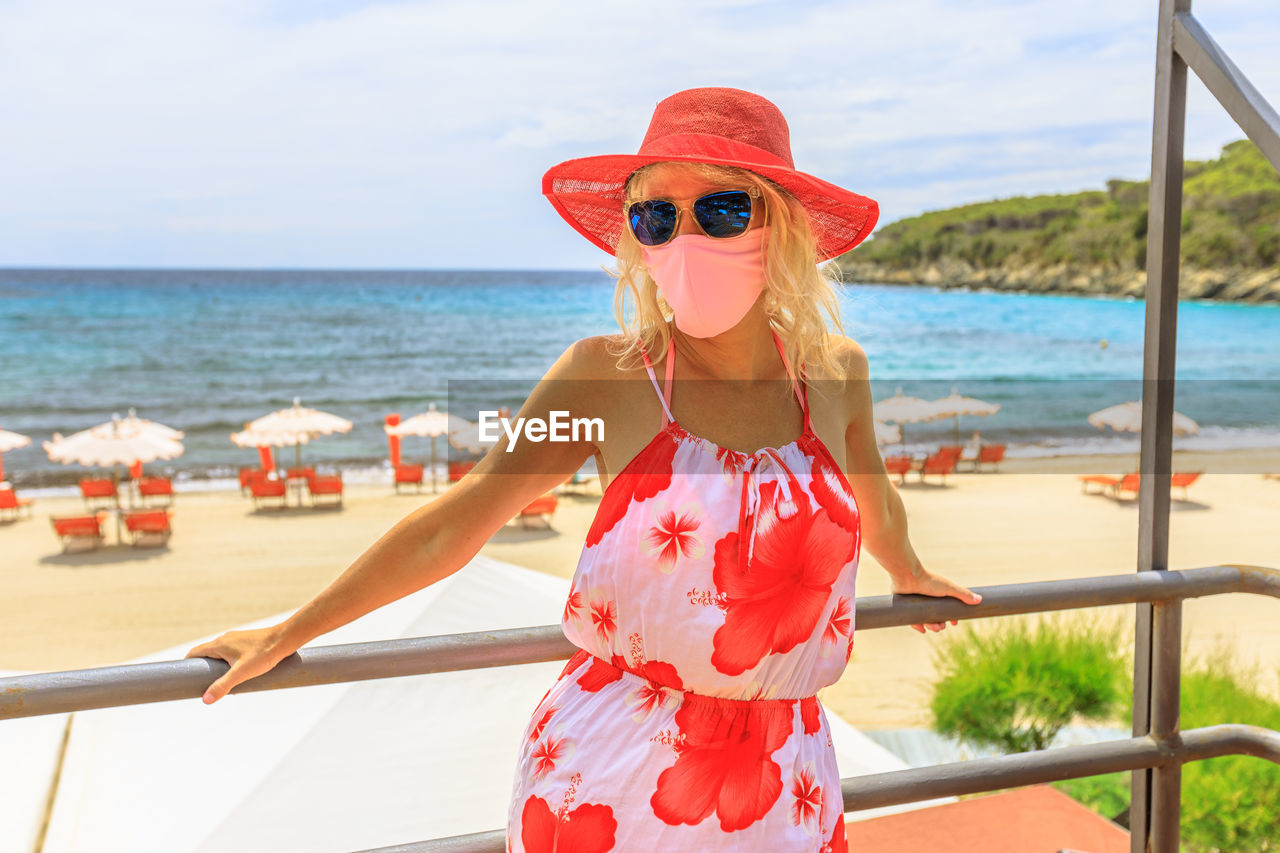 Woman wearing mask standing against sea