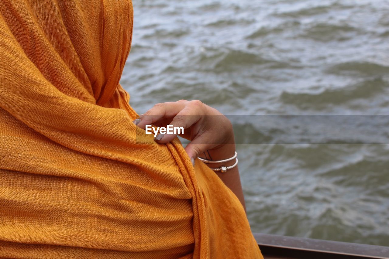 Cropped image of woman with headscarf by railing at liberty island against hudson river