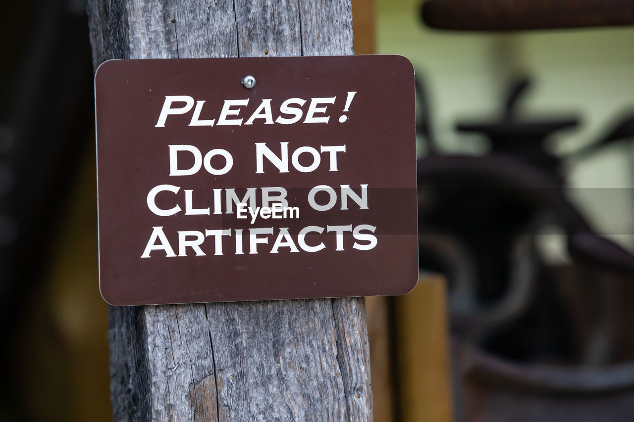 CLOSE-UP OF WARNING SIGN ON WOODEN POST