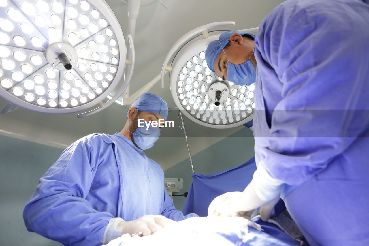 Low angle view of surgeons operating in room