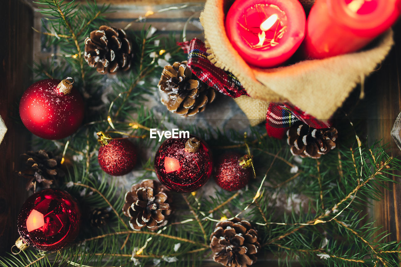 Red christmas decorations on the table at blurred christmas tree with candles . high quality photo