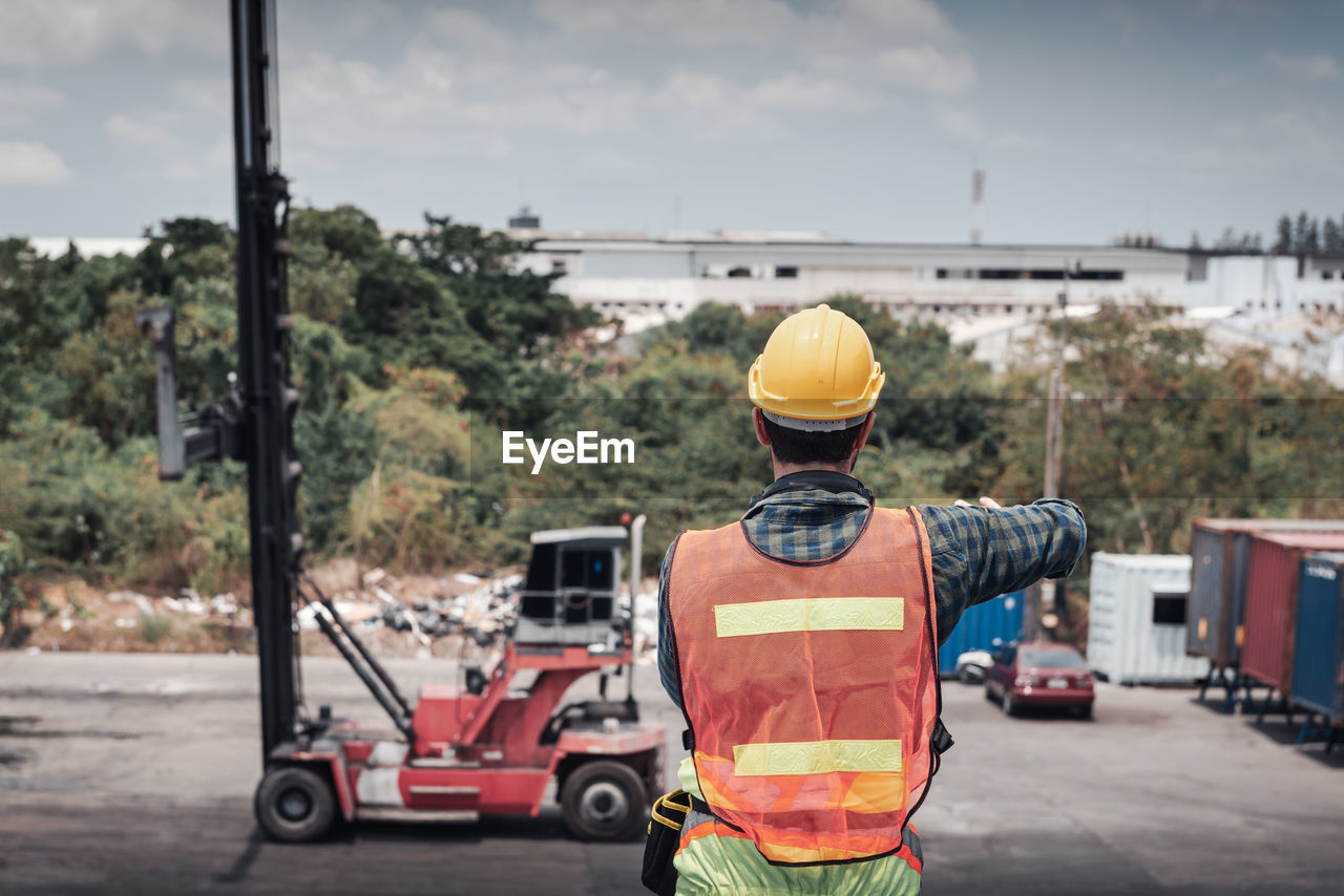 REAR VIEW OF WORKER WORKING ON ROAD