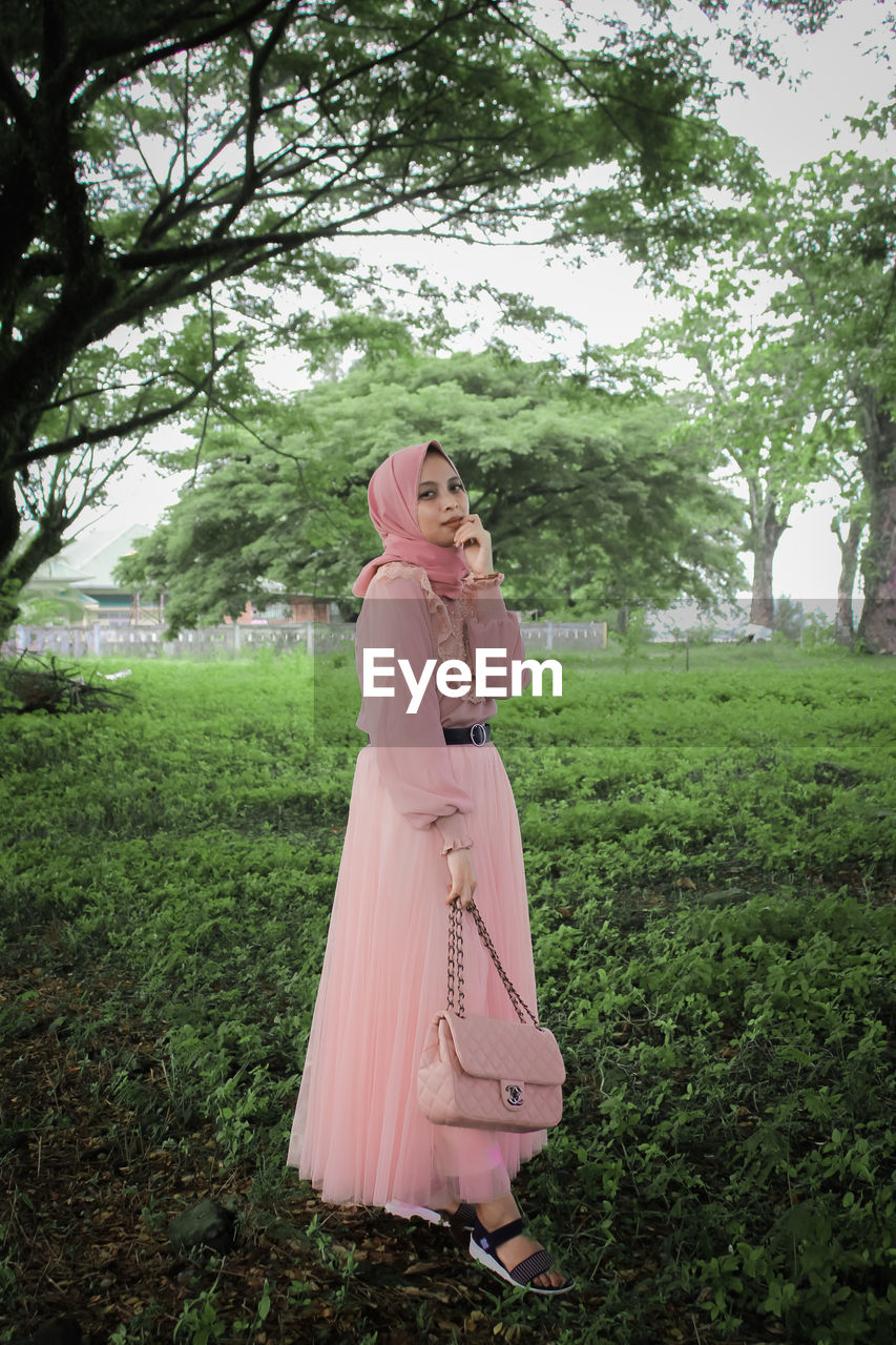 Woman standing by tree on field