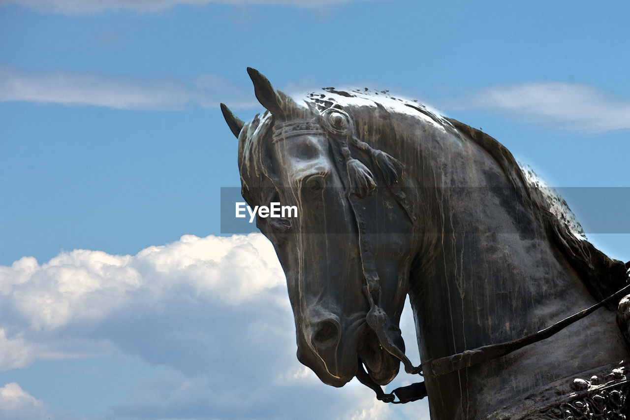 Low angle view of bronze horse statue against sky