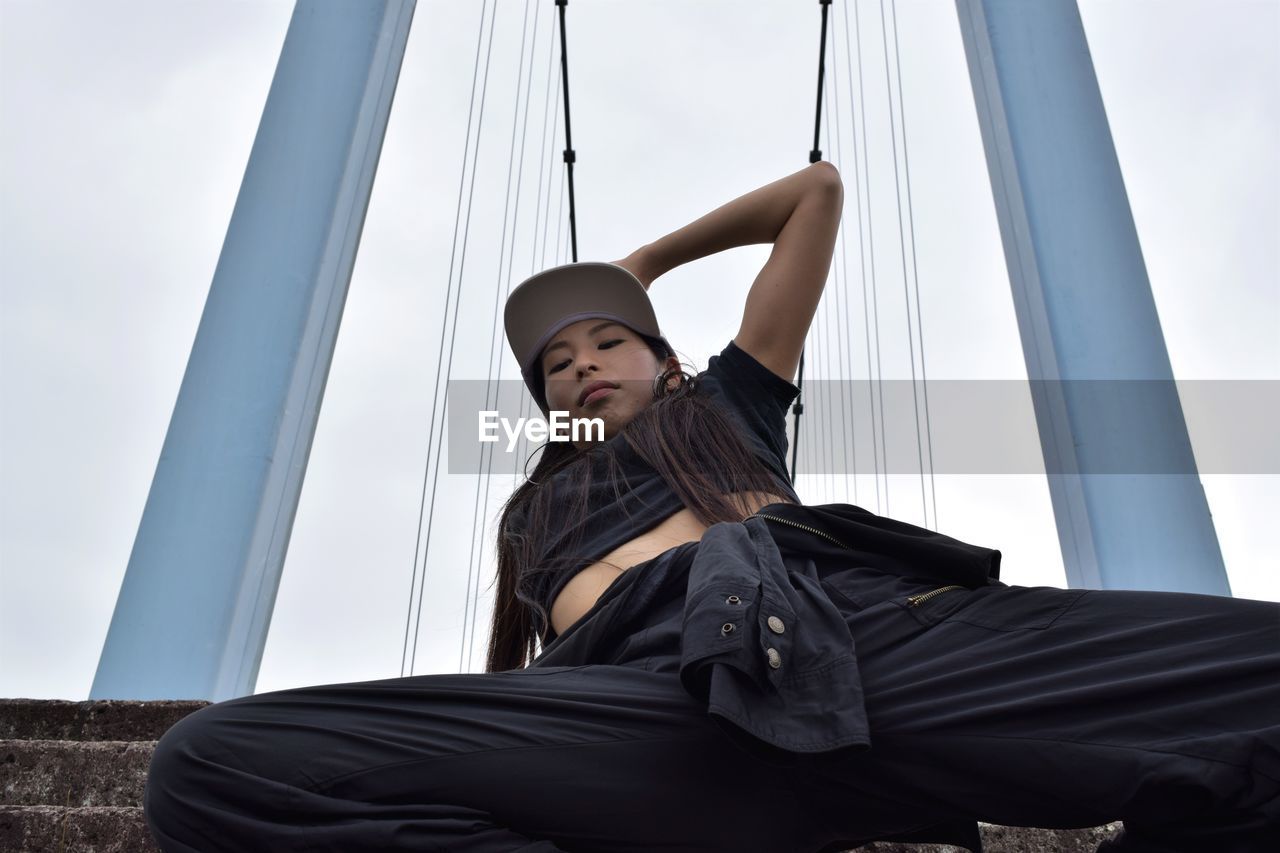 Low angle view of female hip hop dancer against bridge