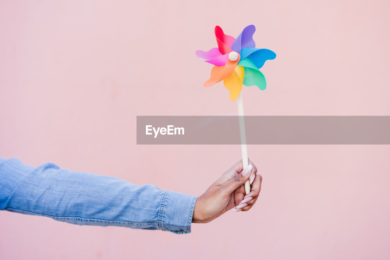 Close up of woman holding colorful pinwheel. pink background,wind energy