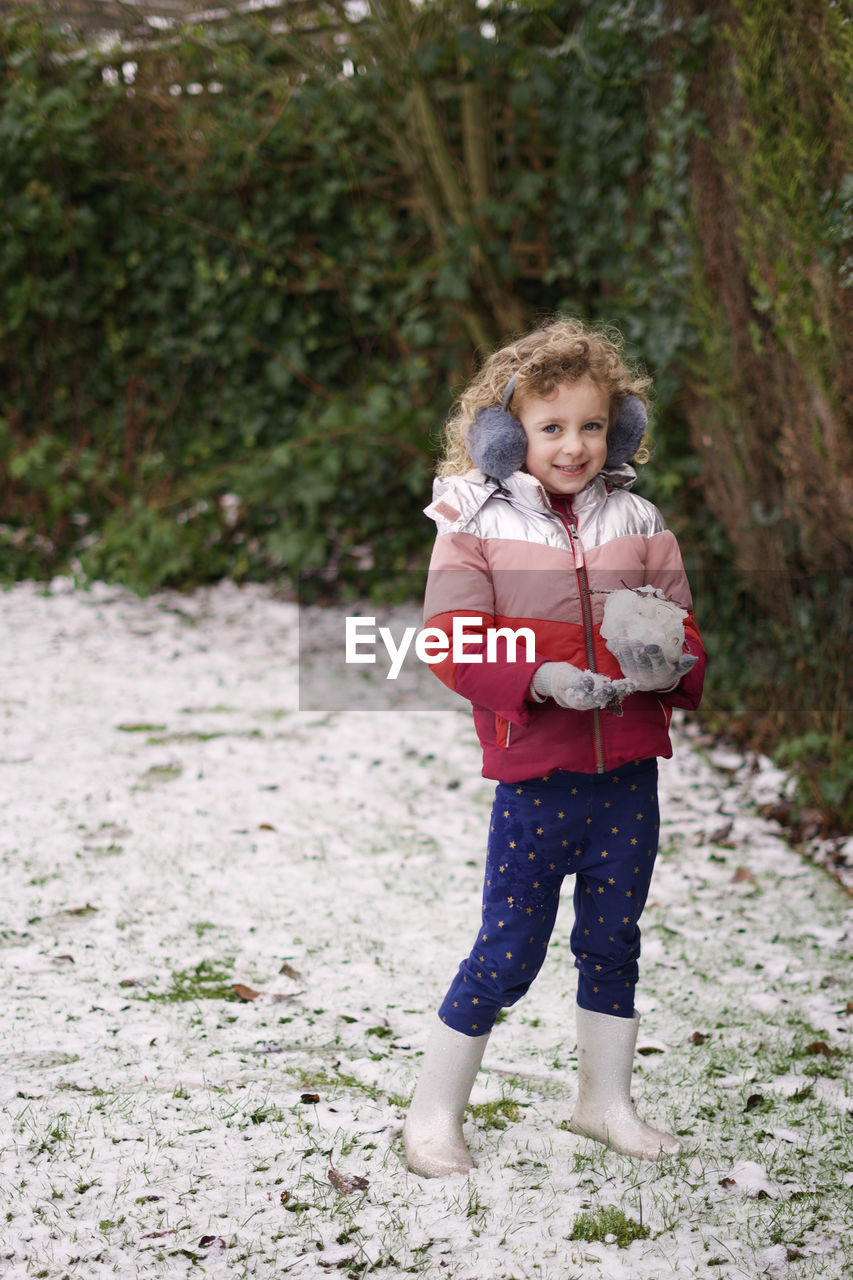 Portrait of a smiling girl standing outdoors in snow