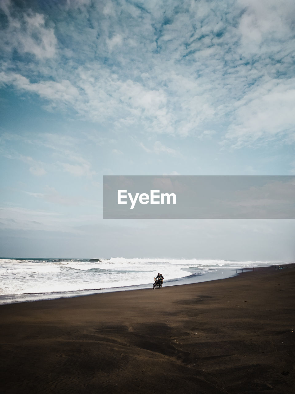 Man riding motorcycle on beach against sky