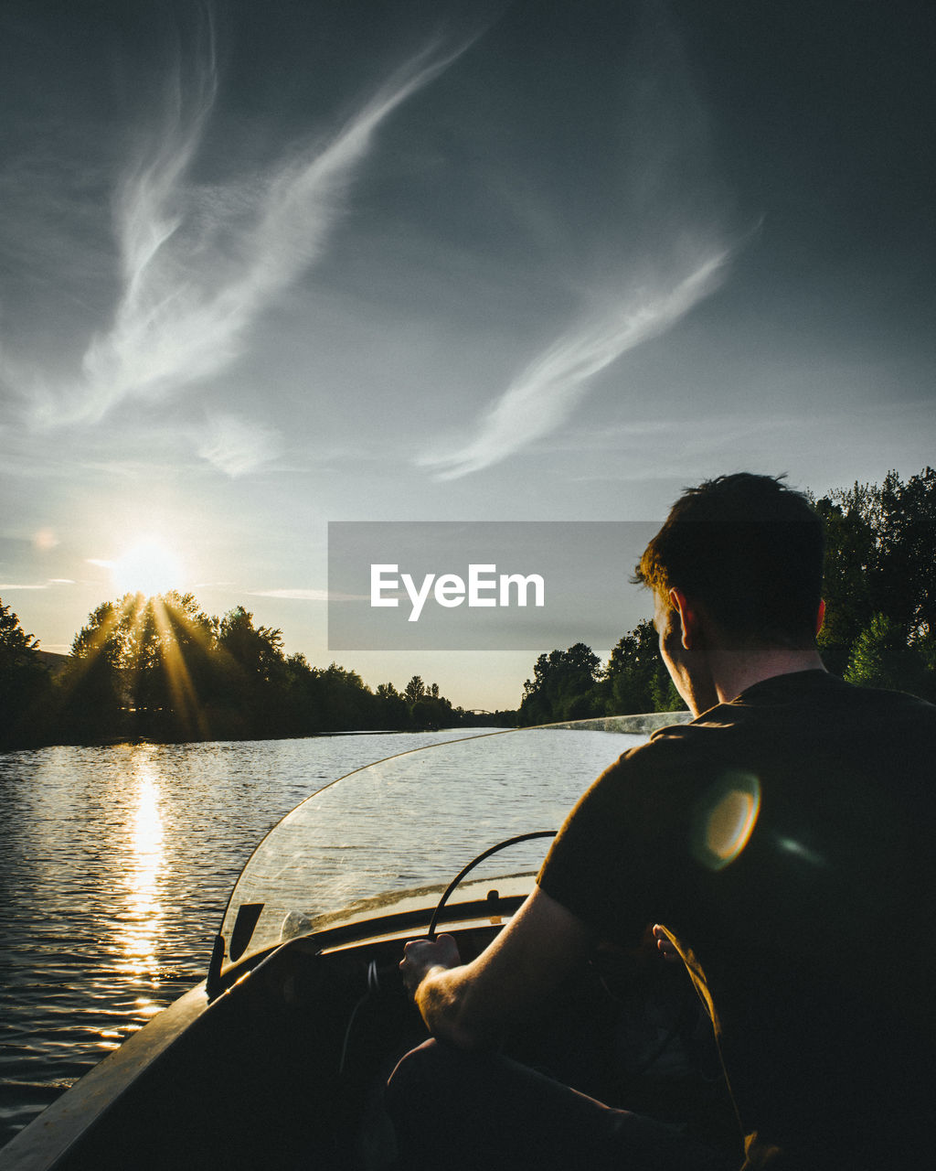 Rear view of man riding speedboat against sky during sunset