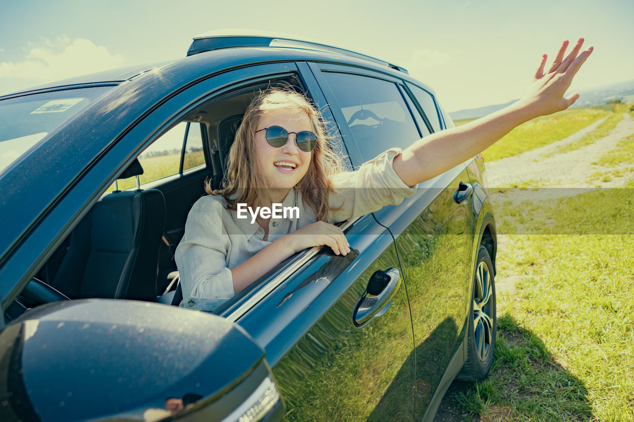 portrait of young woman sitting on car