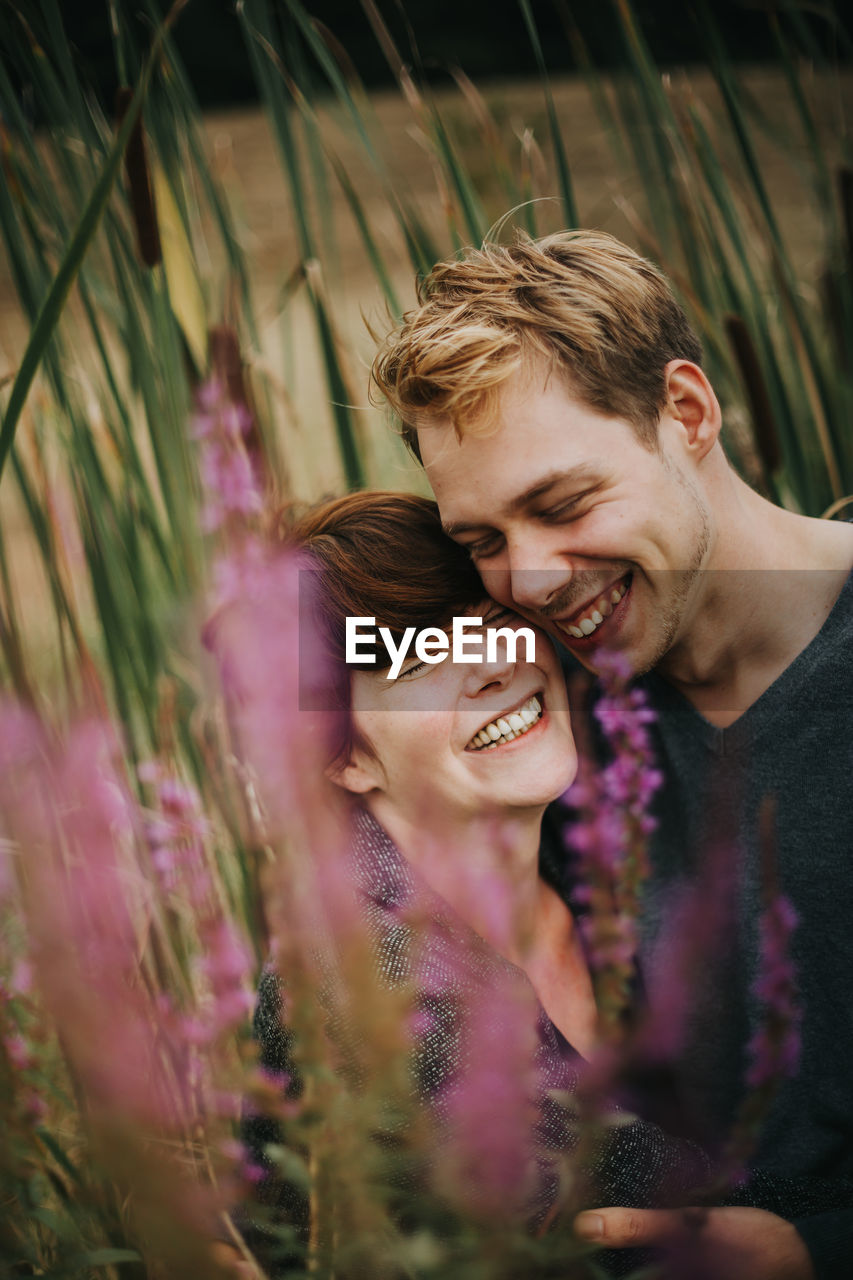 Couple embracing while laughing by plants
