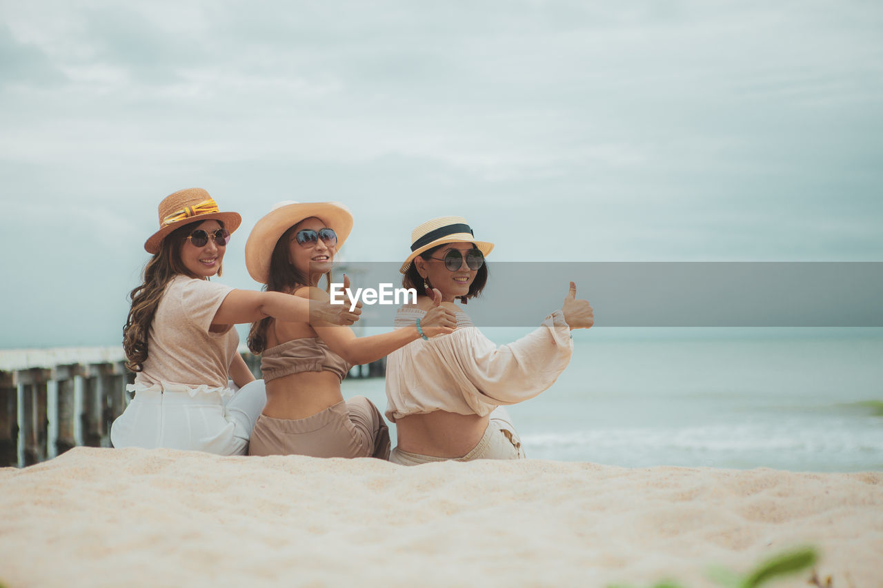 Three asian woman sitting on vacation sea beach with happinessw emotion