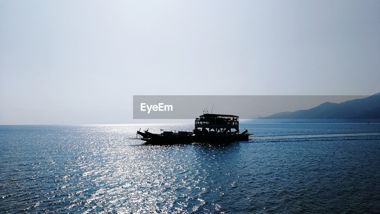 Boat sailing on sea against clear sky