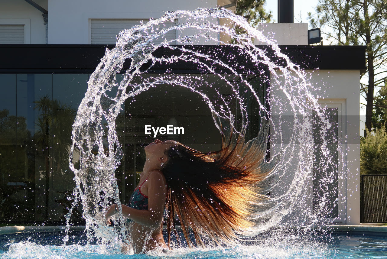 Side view of girl tossing hair in swimming pool