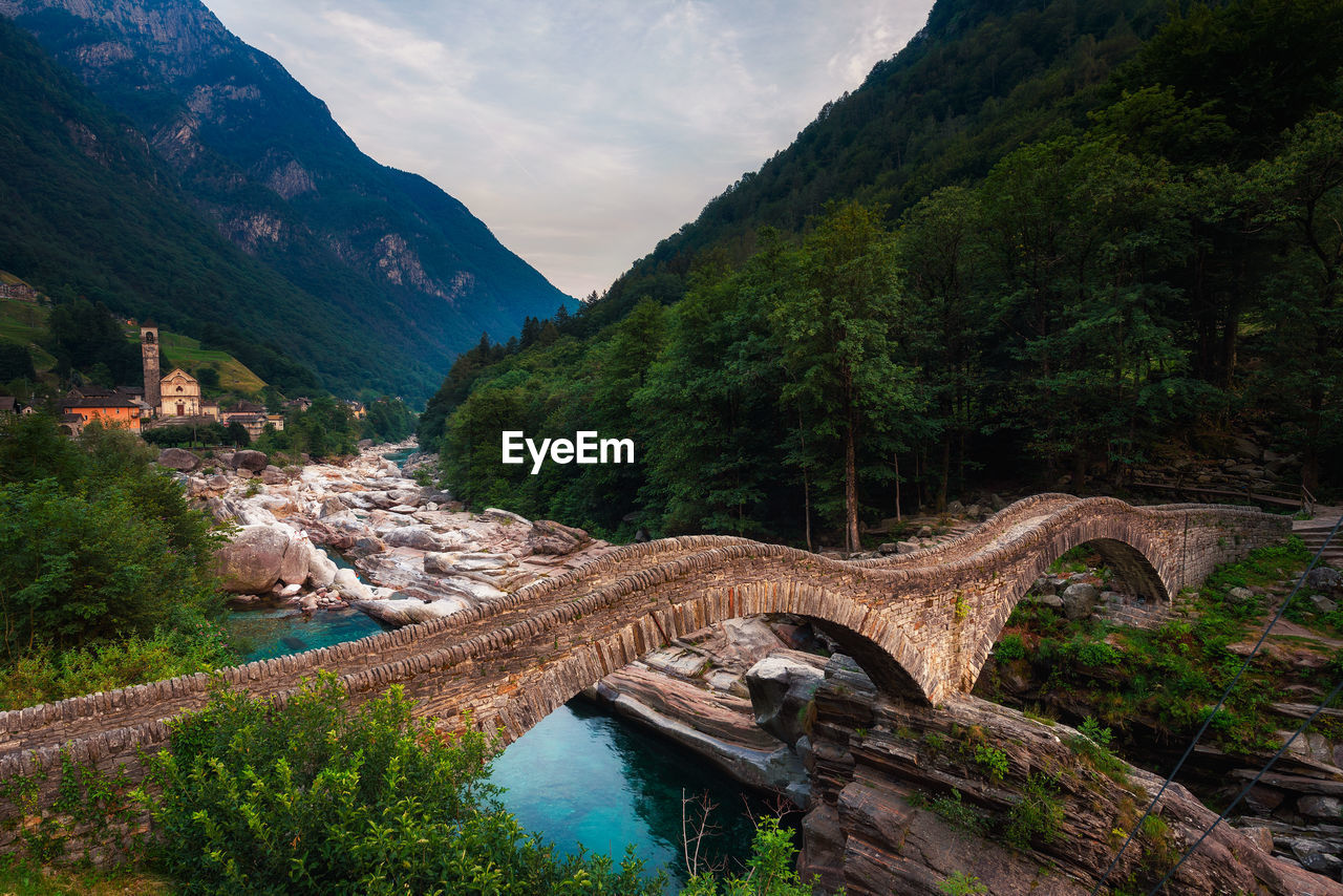 ARCH BRIDGE OVER RIVER AGAINST MOUNTAINS