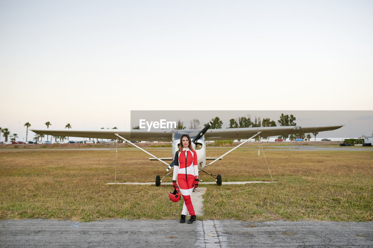 Young female skydiver in an airfield with a plane behind her