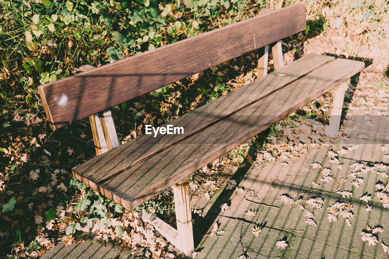 HIGH ANGLE VIEW OF PARK BENCH ON FIELD IN EMPTY FOOTPATH