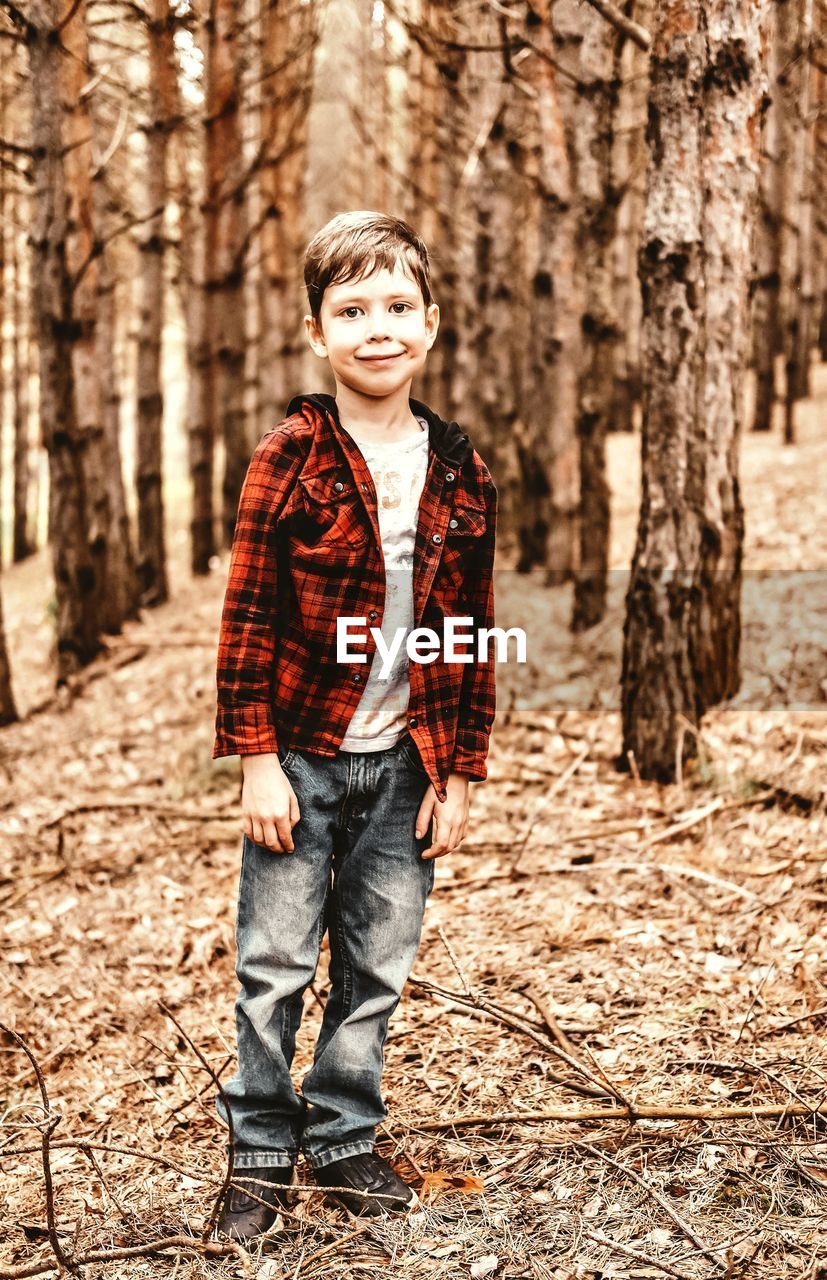 A boy walks in the woods. red shirt and jeans