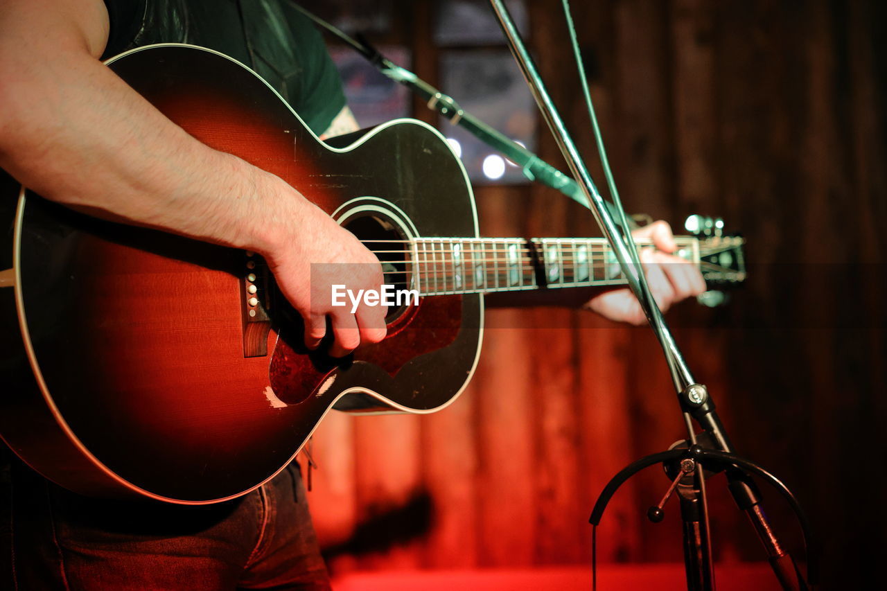 Midsection of man playing guitar