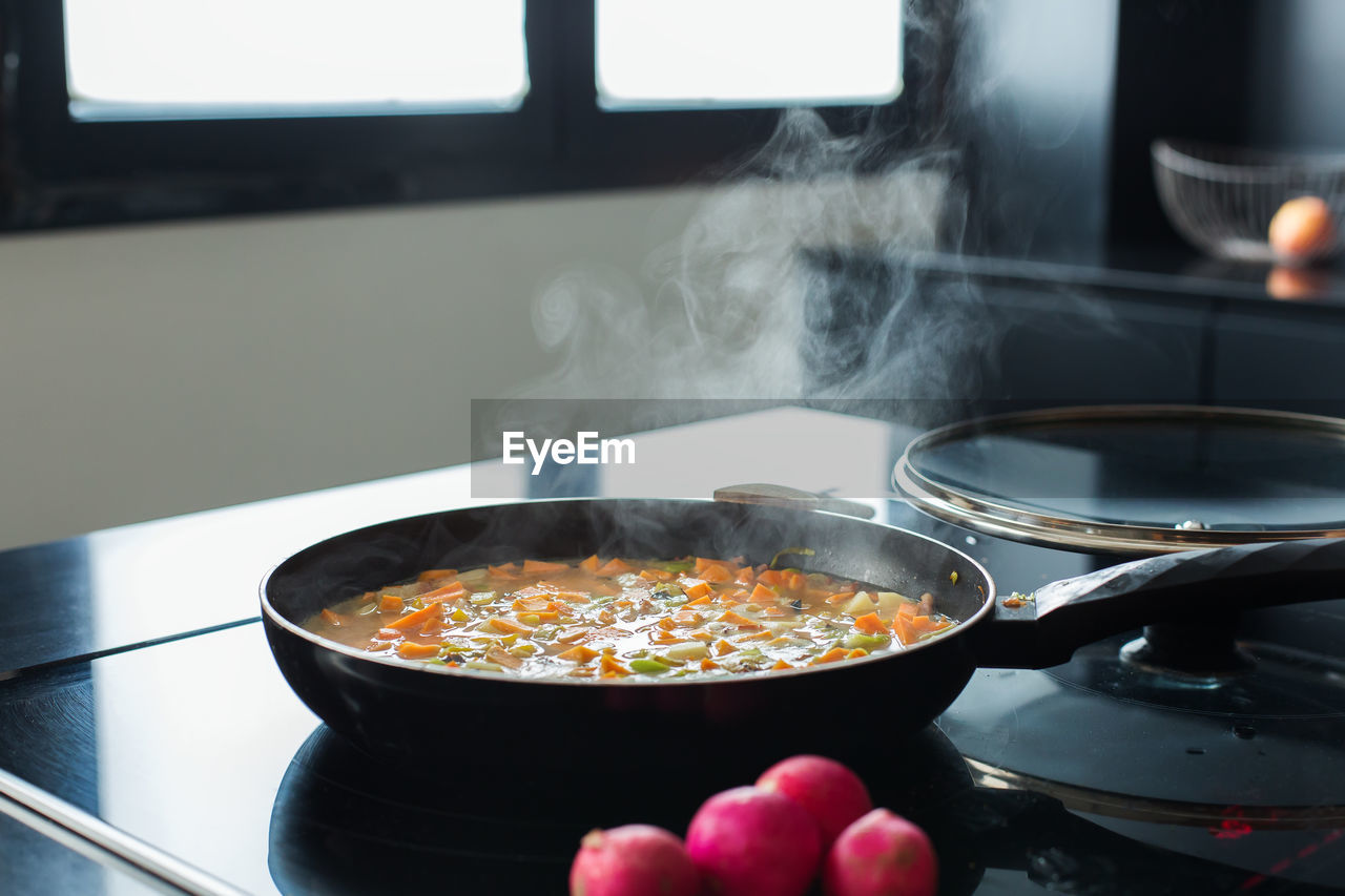 Steaming vegetable stew in a pan at the modern kitchen