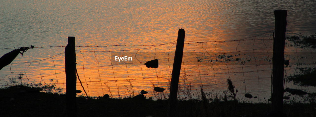 SILHOUETTE WOODEN POST AGAINST SUNSET