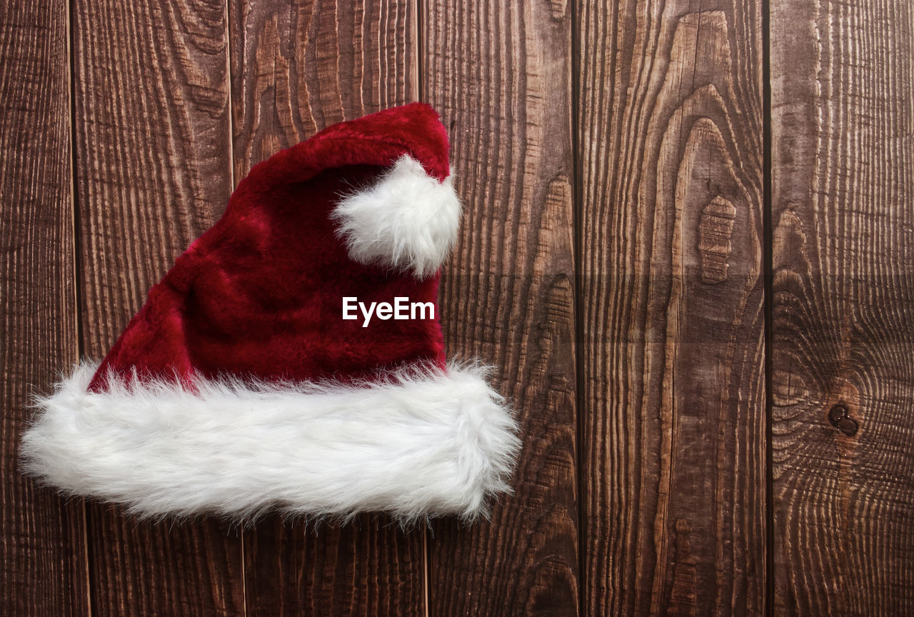 Red santa claus hat isolated on wooden background. space for text. flat lay.