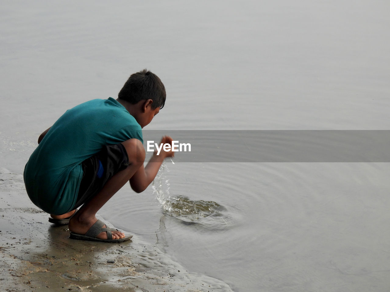 Side view of boy sitting in riverside 