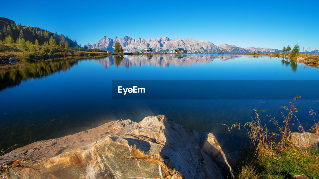 Scenic view of lake and mountains against blue sky