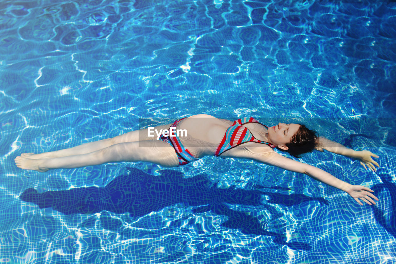 Full length of woman floating in swimming pool