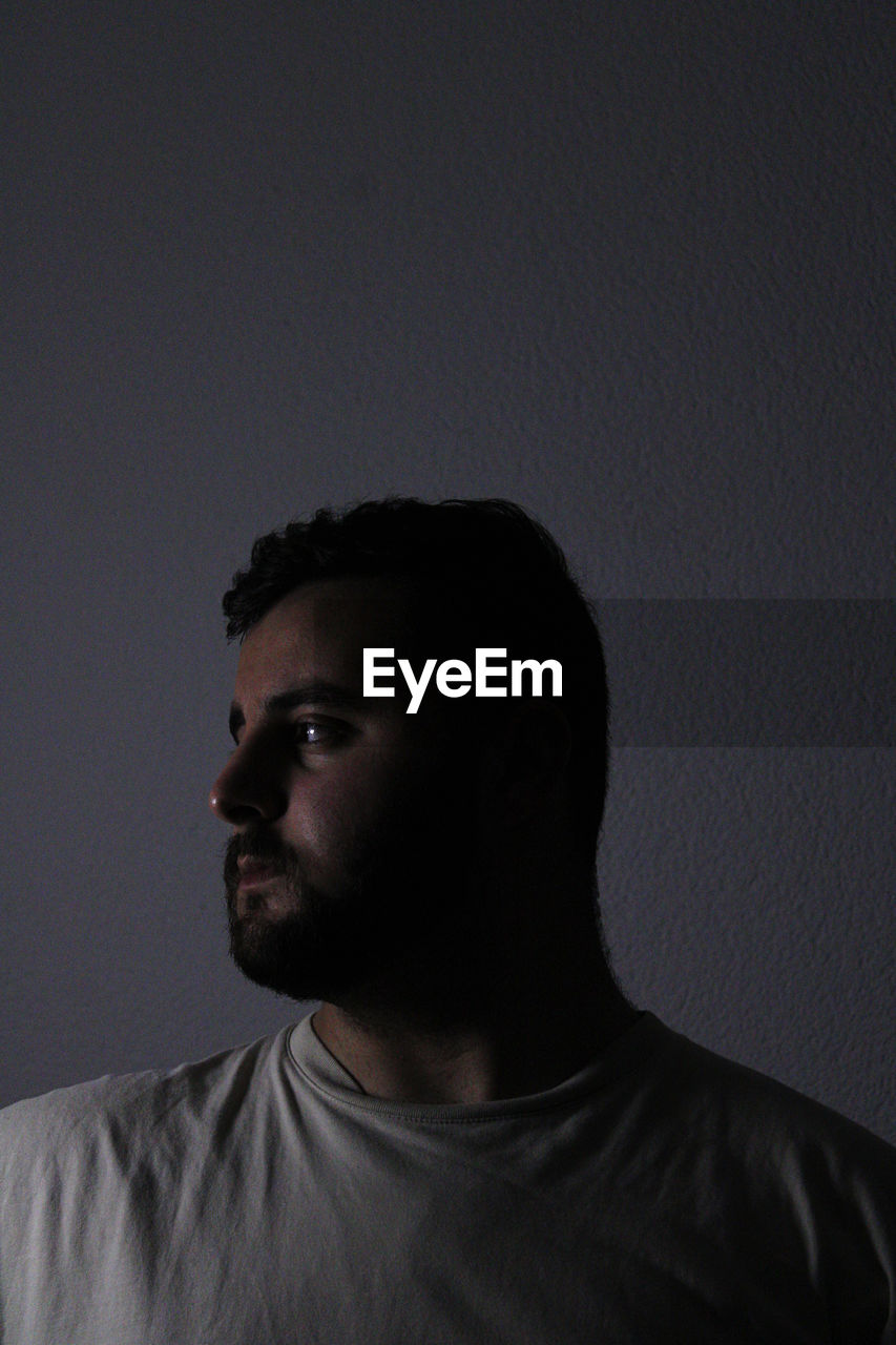 Side view of young man against black background