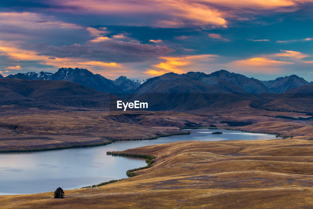 Scenic view of lake by mountains against sky during sunset