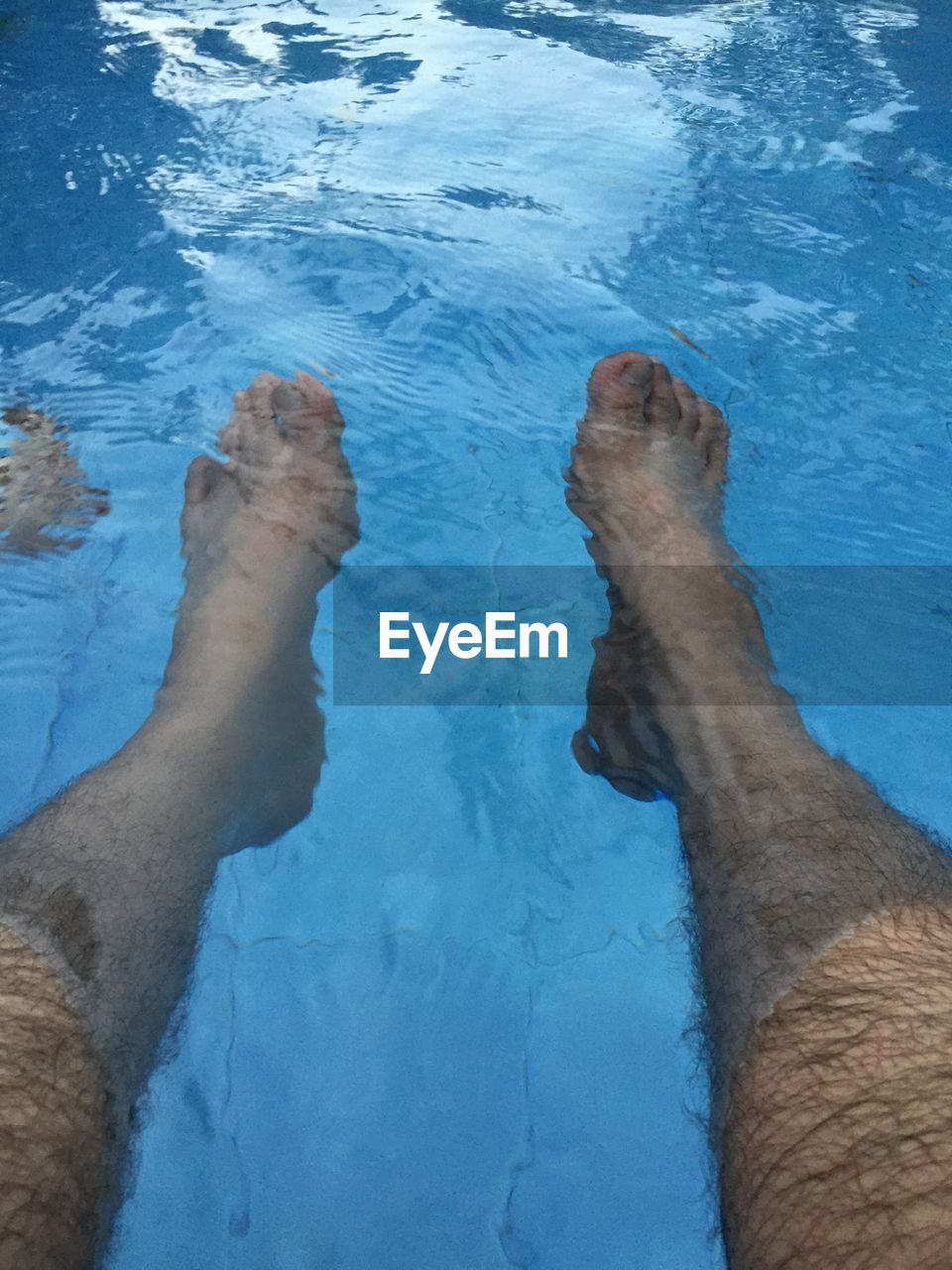 LOW SECTION OF FEET IN WATER AT SWIMMING POOL