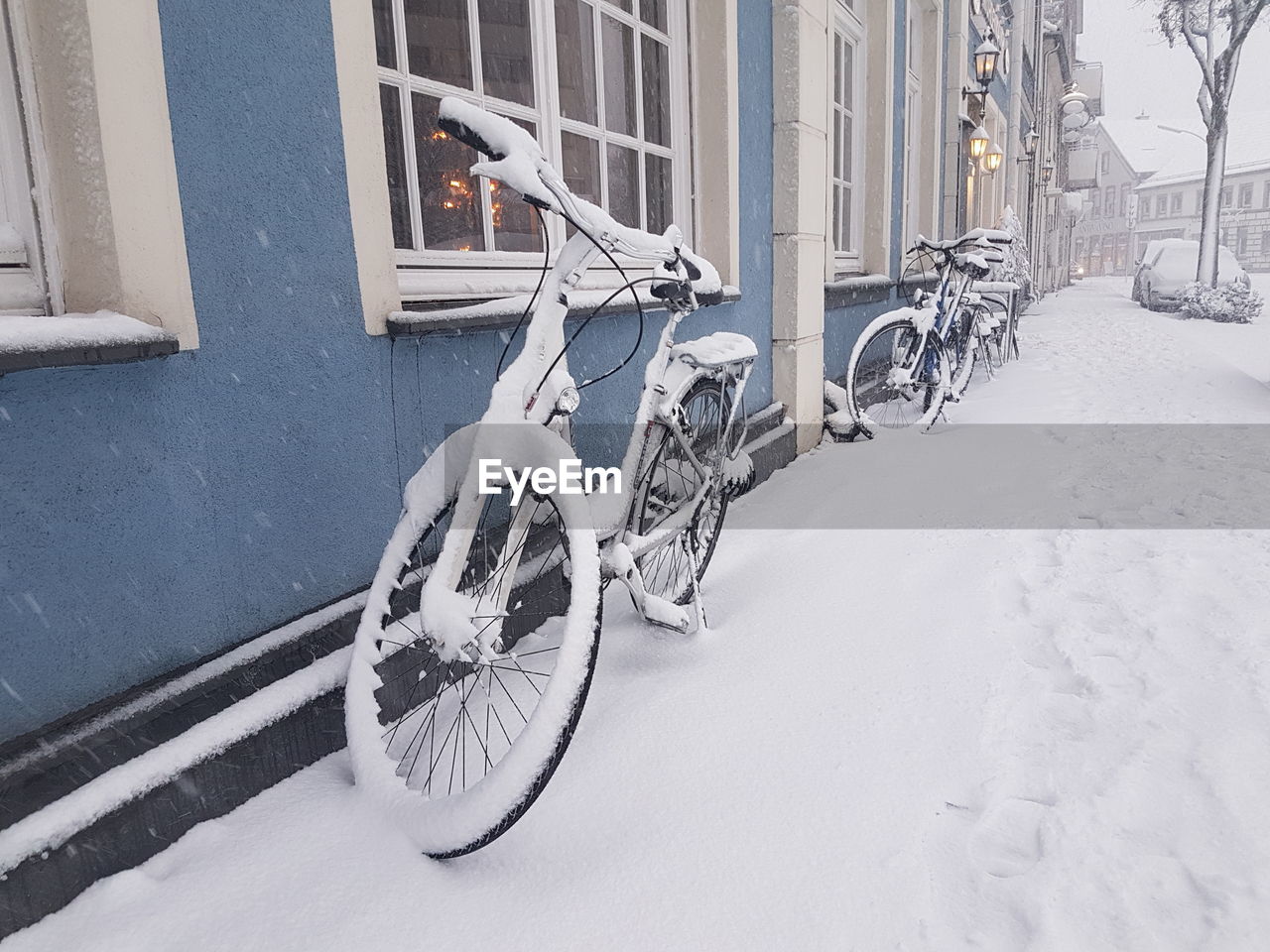 BICYCLE PARKED ON SNOW COVERED CITY
