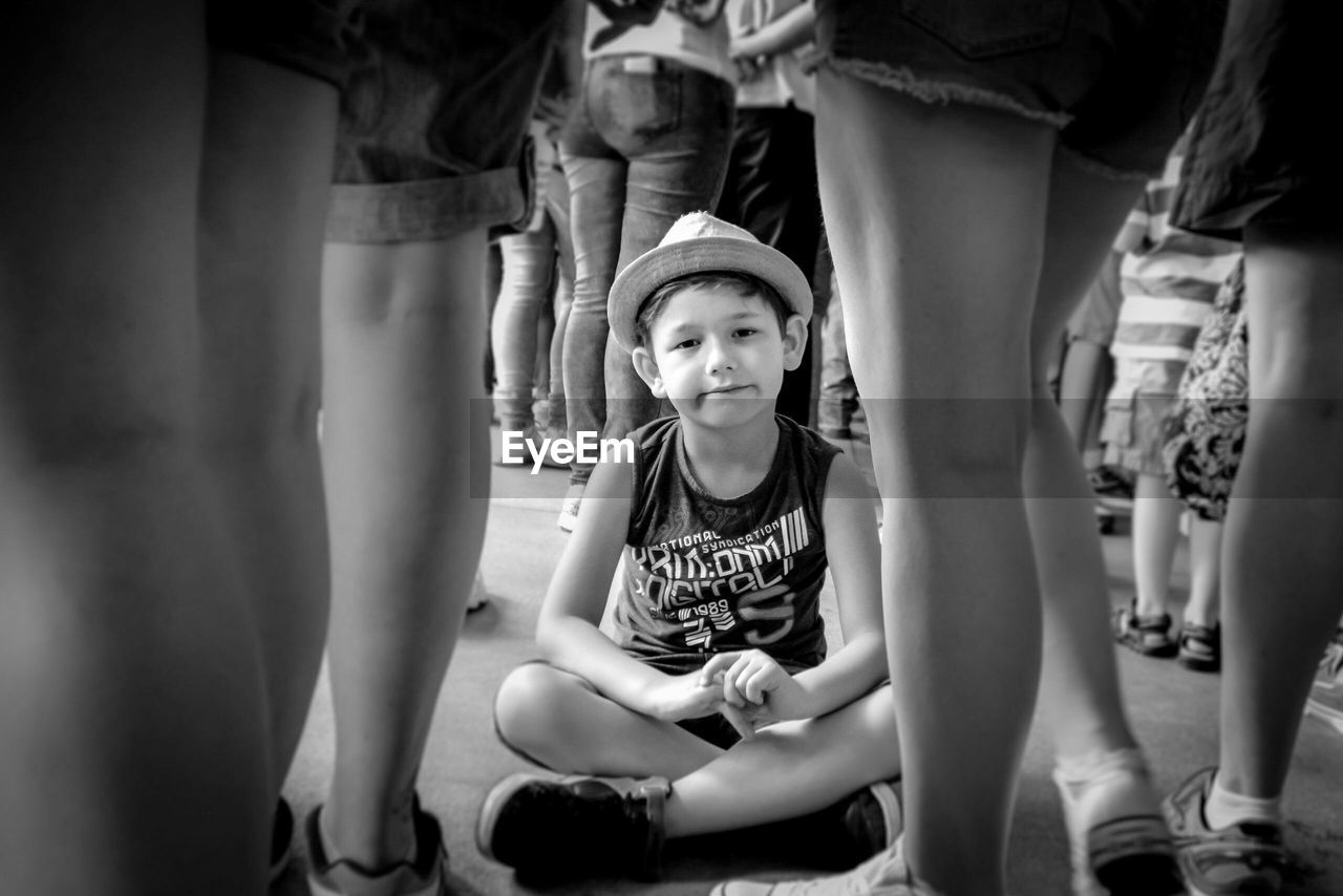 Portrait of boy sitting on street amidst crowd