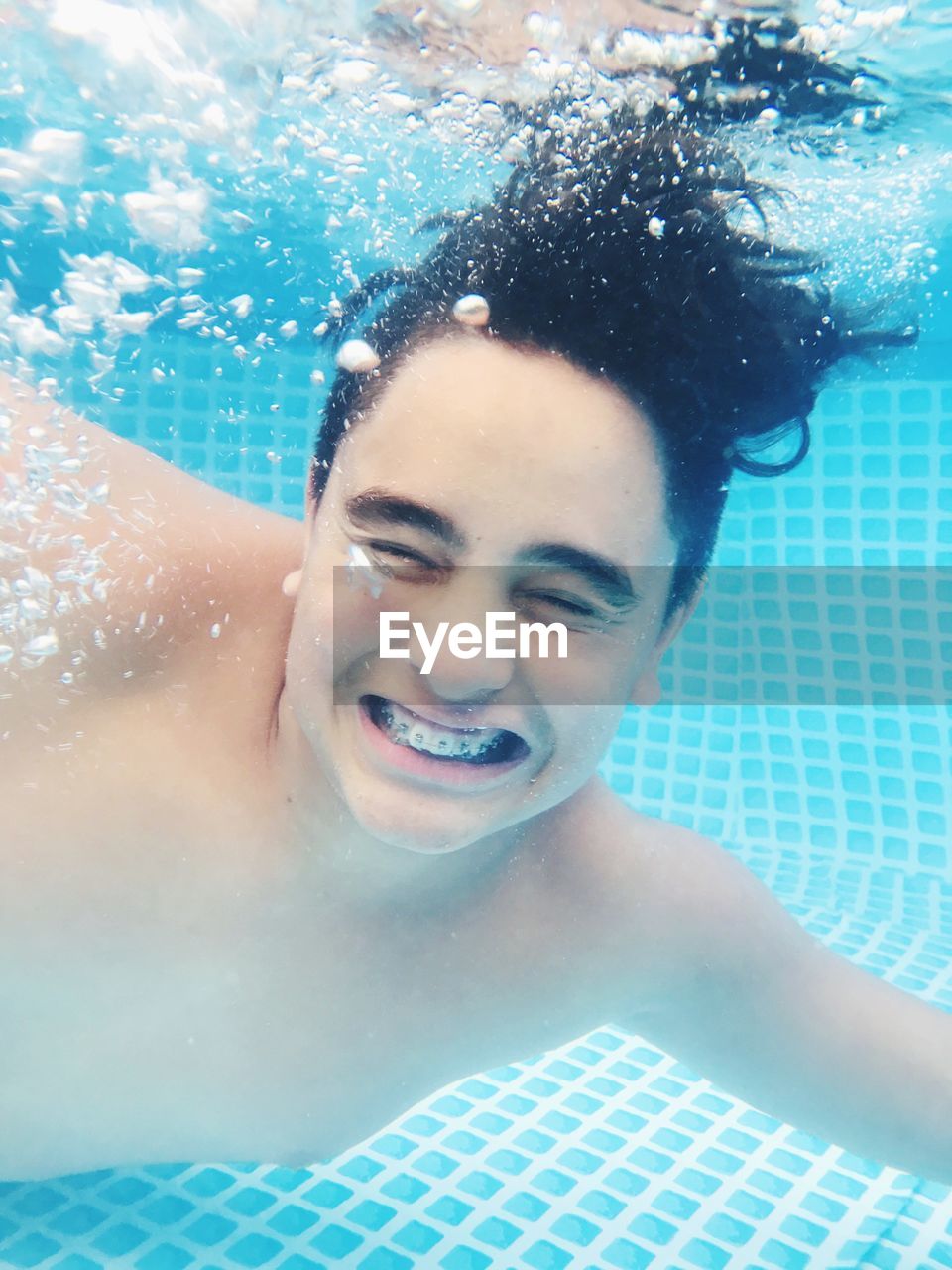 PORTRAIT OF SMILING BOY SWIMMING IN POOL