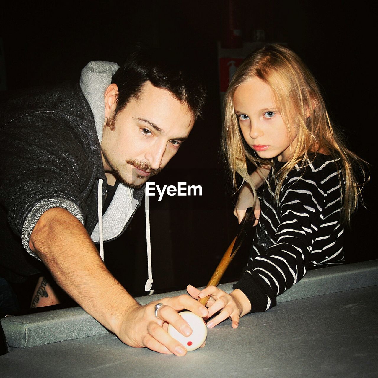 Portrait of daughter with father playing pool