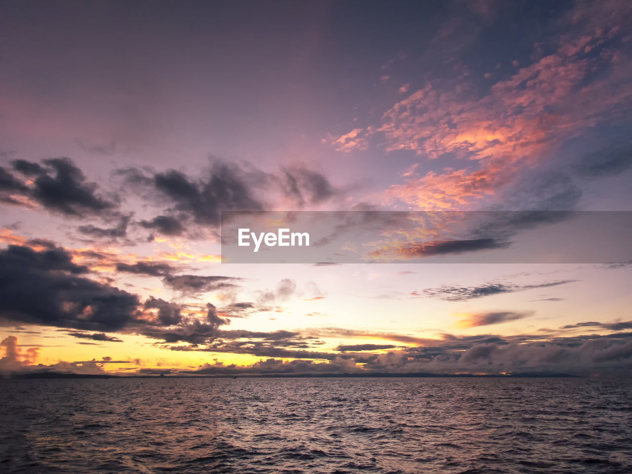 Scenic view of sea against dramatic sky during sunset