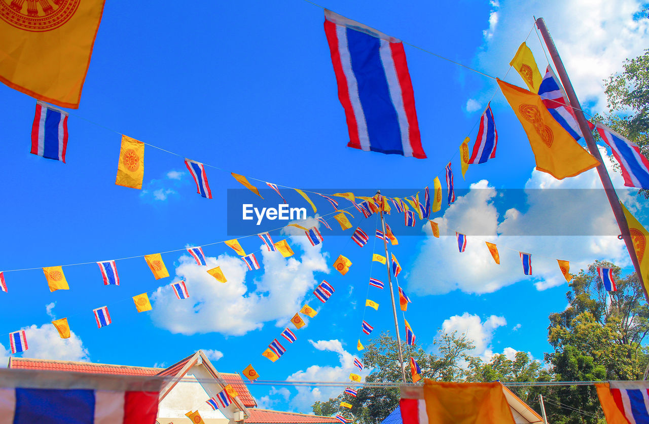 Low angle view of thai flags against sky