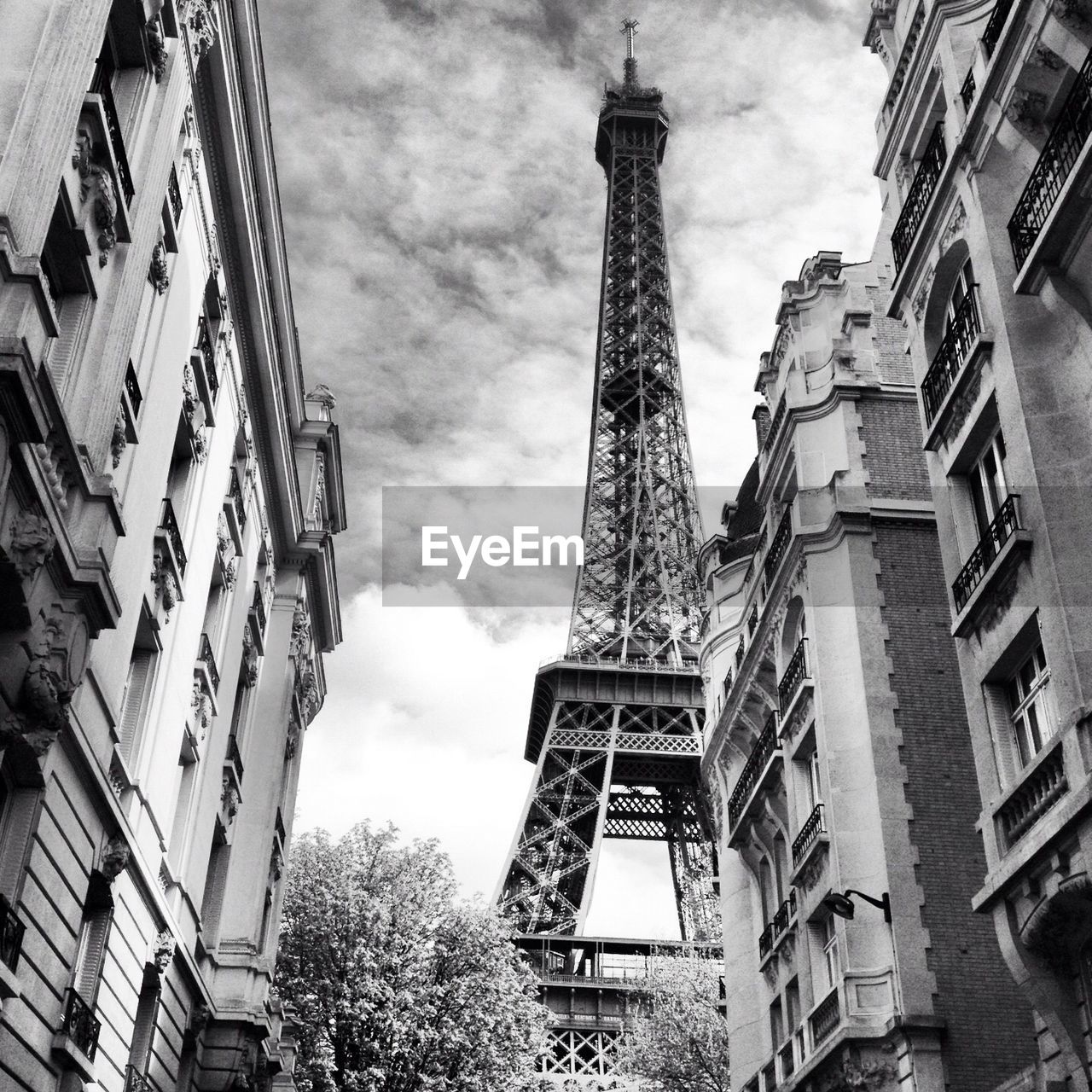 Low angle view of eiffel tower amidst buildings in city against cloudy sky
