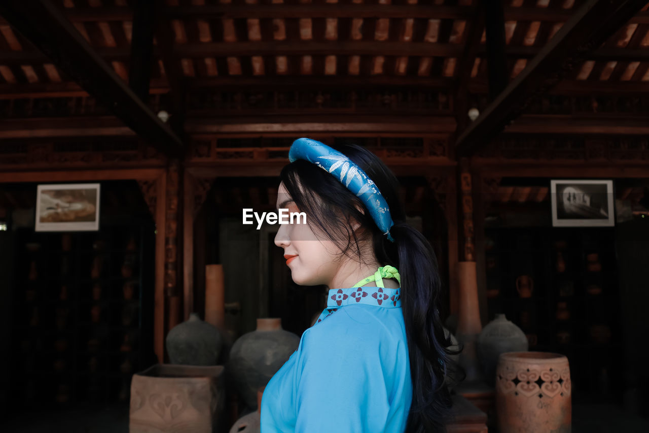 Portrait of young woman standing outside house