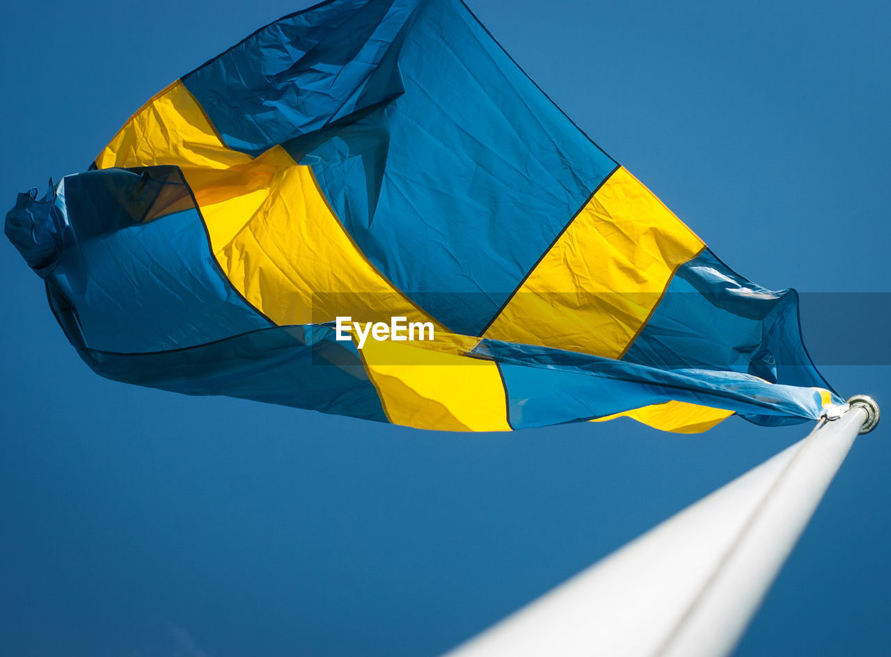 Low angle view of swedish flag waving against clear sky