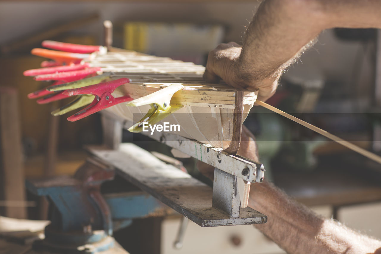 Close-up of man working on wooden boat model