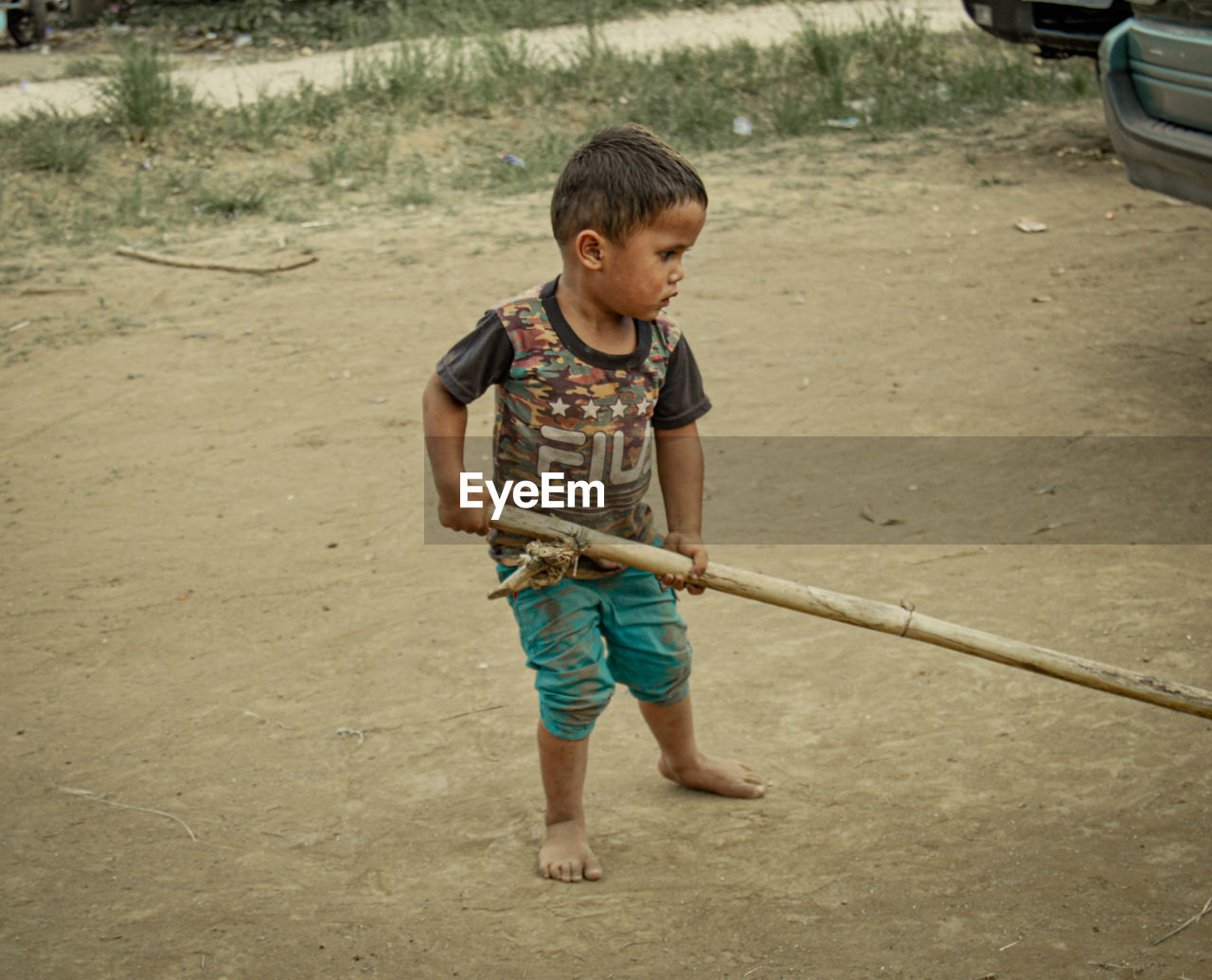 childhood, child, one person, men, full length, casual clothing, toddler, front view, standing, day, vehicle, car, nature, leisure activity, person, innocence, land, sand, lifestyles, outdoors, transportation, looking, land vehicle, holding, cute, mode of transportation