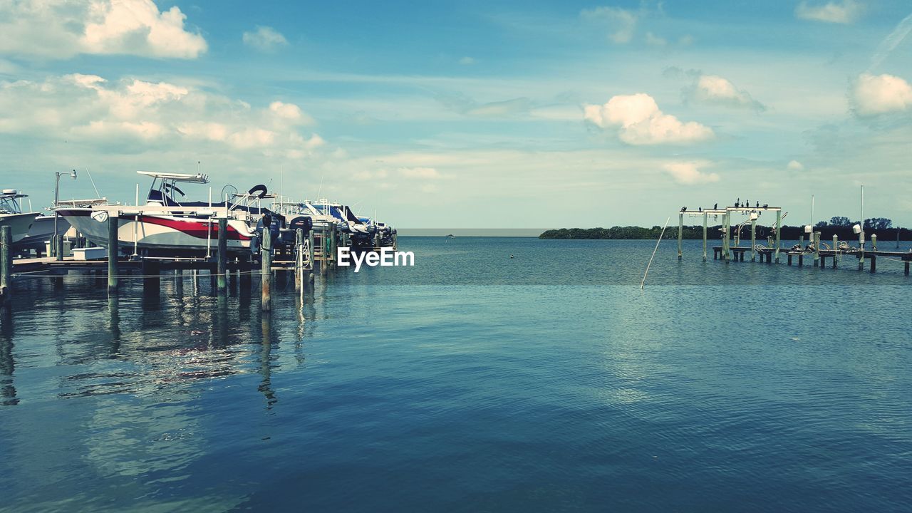 Boats moored on pier at sea against sky