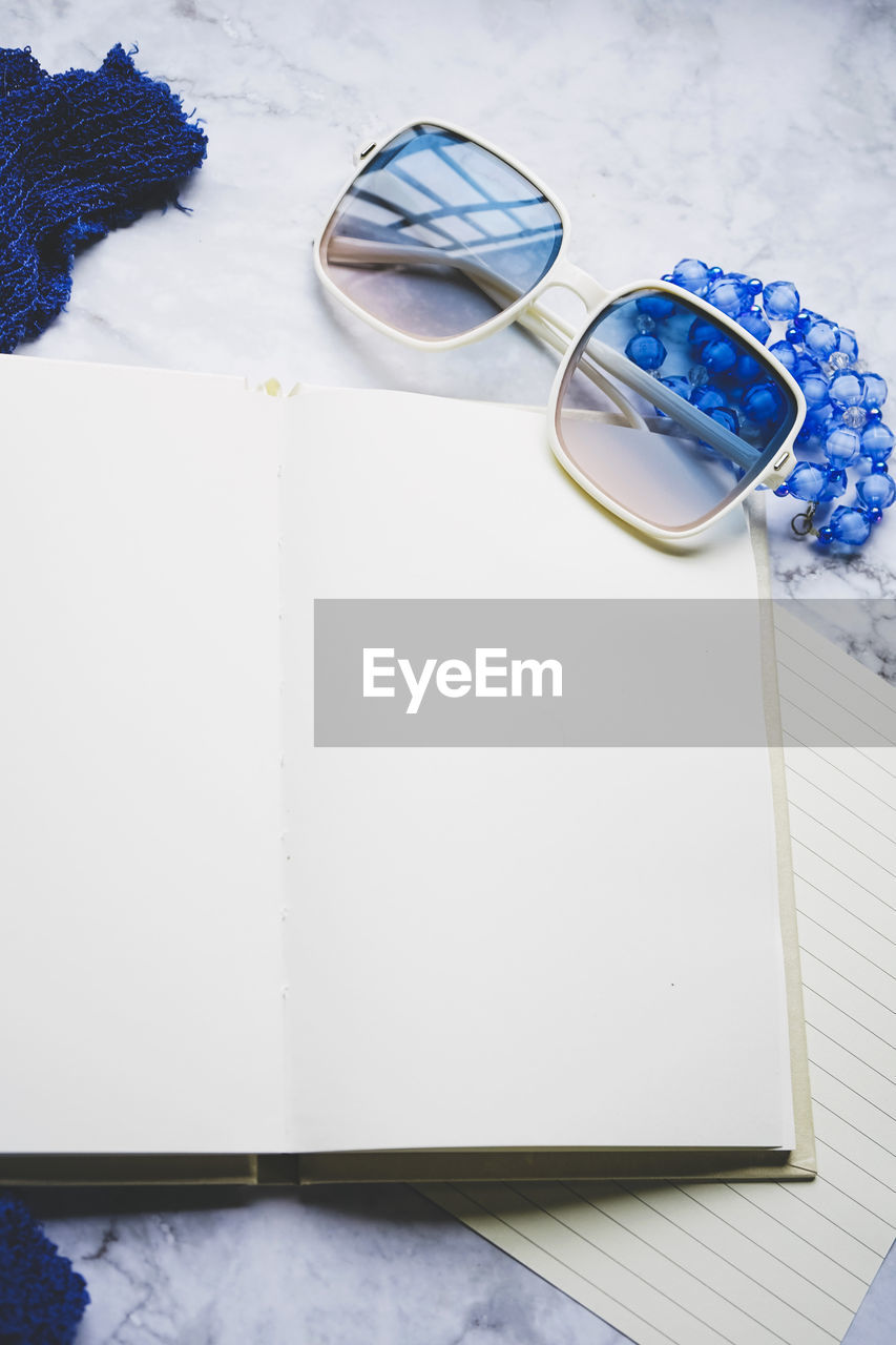 high angle view of sunglasses and book with eyeglasses on table