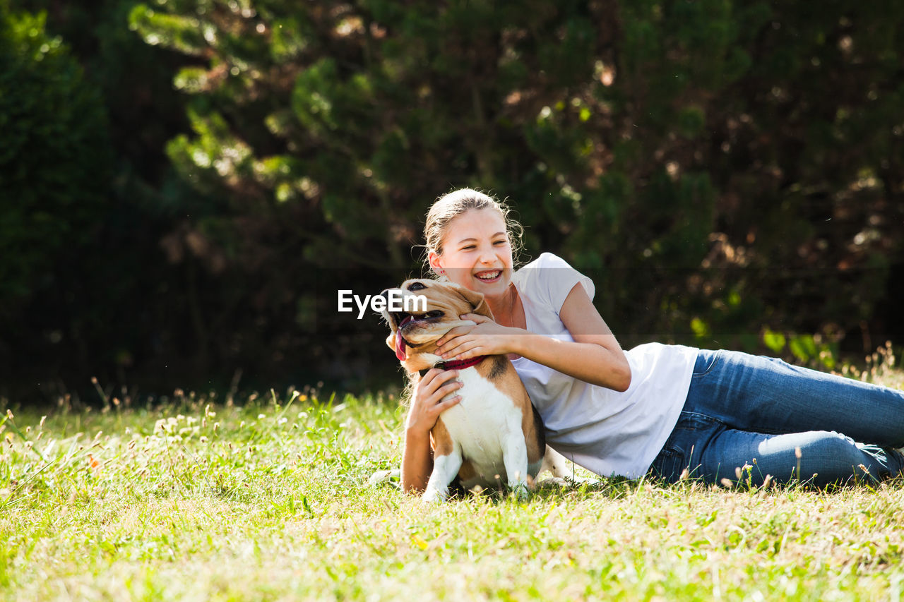 Girl with dog on grass against trees